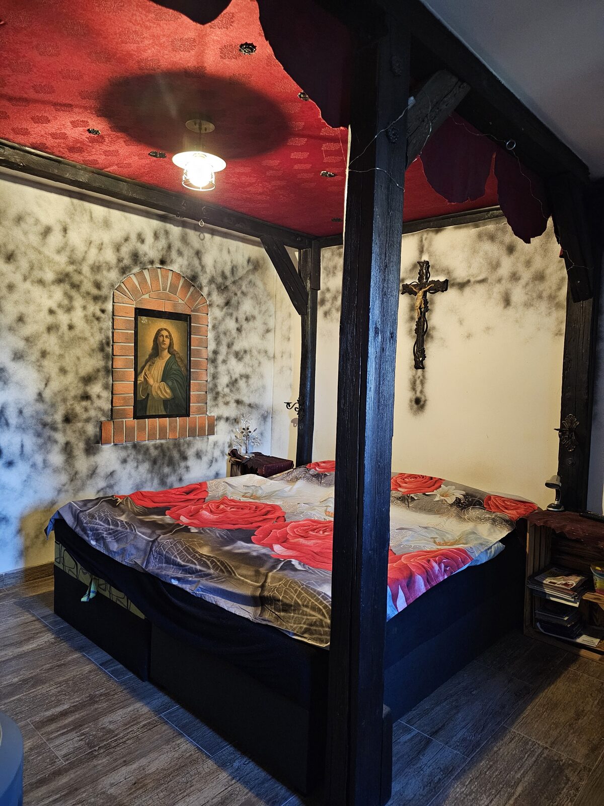 Ložnice s nebesovou postelí, obrazem Madony a křížem na kamenné stěně